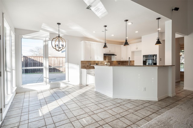 kitchen featuring black oven, white cabinetry, tasteful backsplash, light tile patterned flooring, and a chandelier