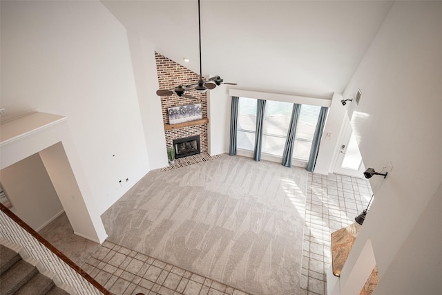 unfurnished living room featuring ceiling fan, light colored carpet, a fireplace, and high vaulted ceiling