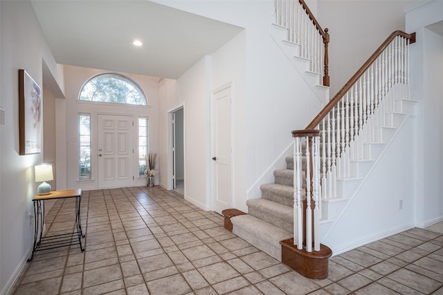 entryway with a towering ceiling and light tile patterned floors