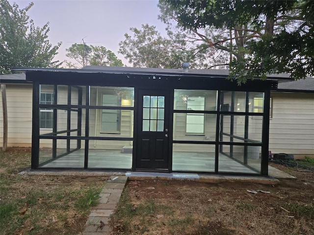 back house at dusk featuring a sunroom