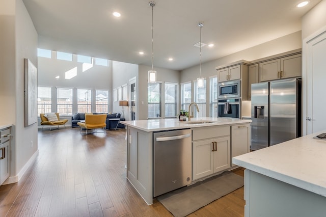 kitchen featuring appliances with stainless steel finishes, sink, an island with sink, and a healthy amount of sunlight