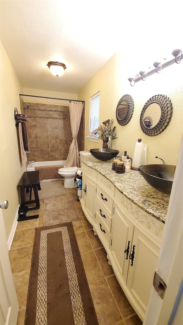 full bathroom featuring vanity, shower / bath combo, tile patterned flooring, toilet, and a textured ceiling