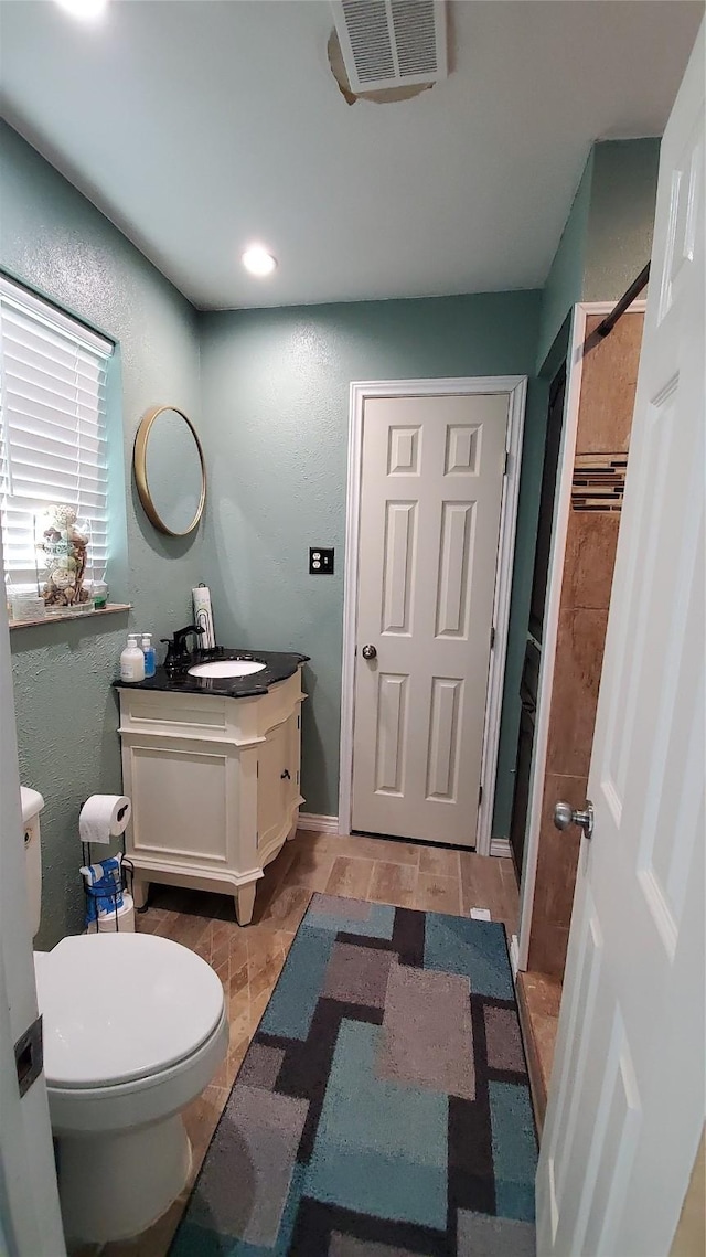 bathroom featuring tile patterned flooring, toilet, vanity, and tiled shower