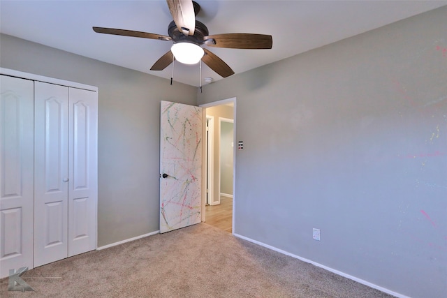 unfurnished bedroom with light colored carpet, ceiling fan, and a closet