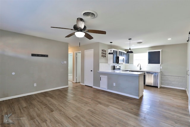 kitchen with stainless steel appliances, hardwood / wood-style floors, kitchen peninsula, ceiling fan, and decorative light fixtures