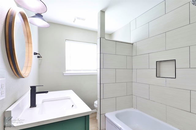 full bathroom featuring toilet, vanity, and tiled shower / bath