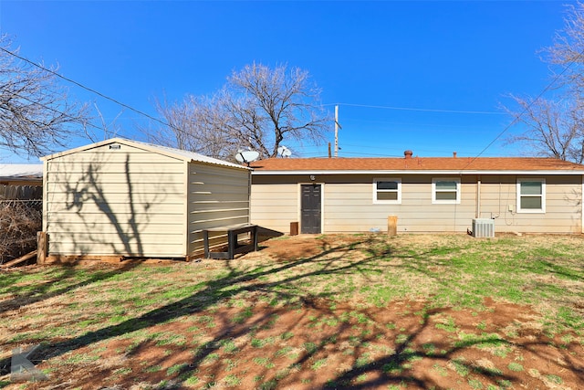 rear view of property featuring a shed, central AC, and a yard