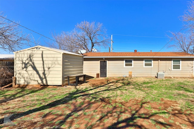 rear view of property featuring a yard, central AC, and a shed