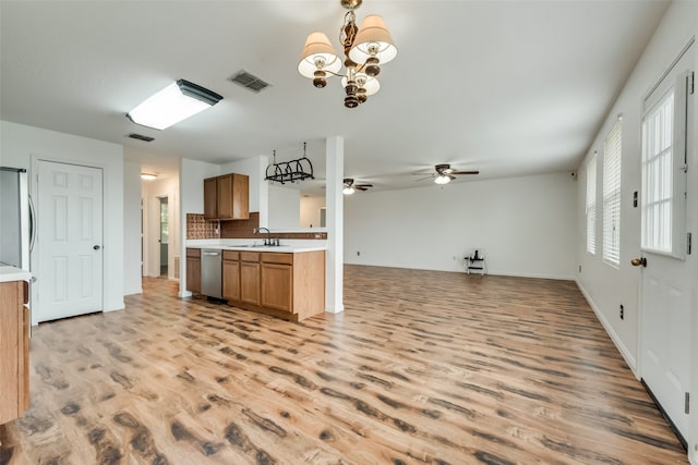 kitchen featuring decorative backsplash, appliances with stainless steel finishes, light wood-type flooring, ceiling fan with notable chandelier, and sink