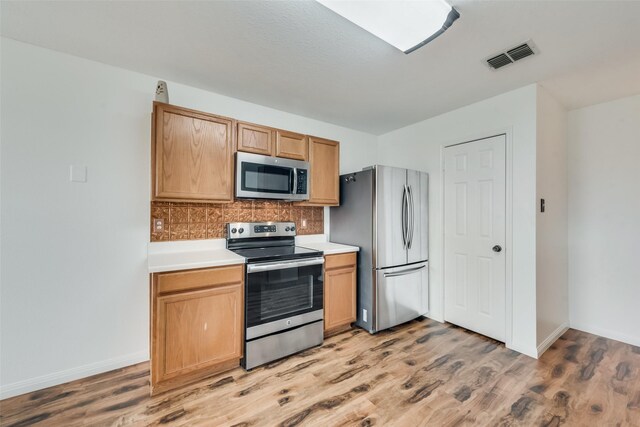 kitchen featuring appliances with stainless steel finishes, backsplash, and light hardwood / wood-style floors