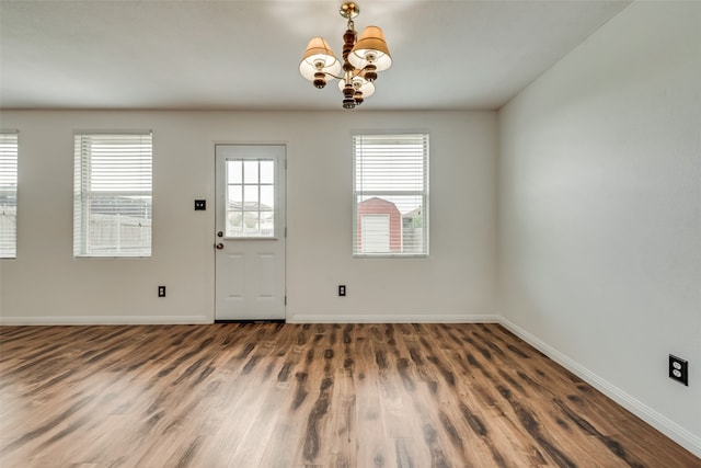 foyer with dark hardwood / wood-style floors, a healthy amount of sunlight, and an inviting chandelier