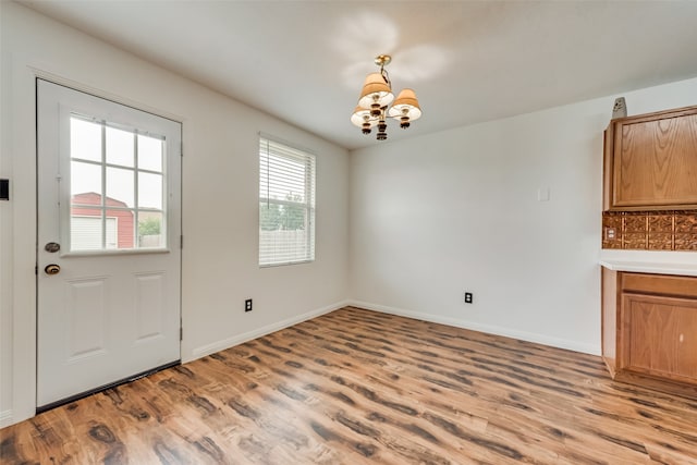 unfurnished dining area featuring light hardwood / wood-style floors and a notable chandelier