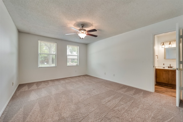 spare room with ceiling fan, sink, light colored carpet, and a textured ceiling