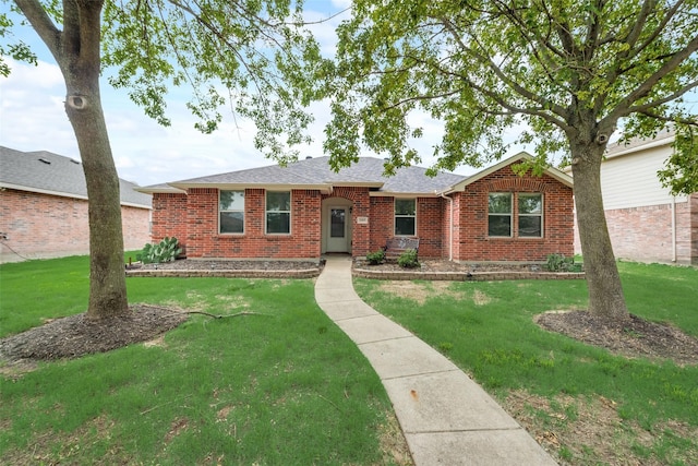 single story home featuring brick siding, roof with shingles, and a front yard