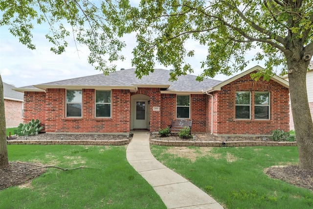 ranch-style home with a front yard, brick siding, and a shingled roof