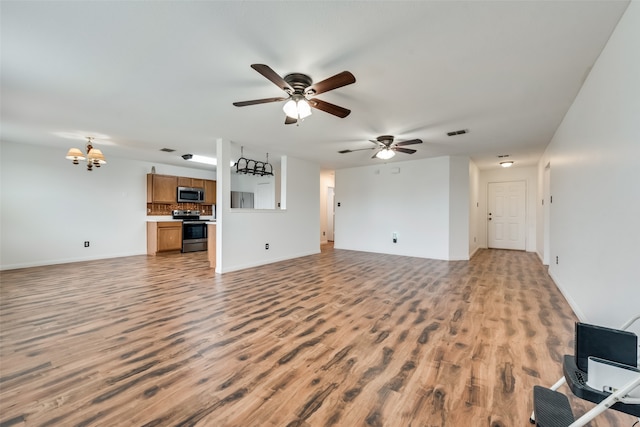 unfurnished living room with ceiling fan with notable chandelier and light wood-type flooring