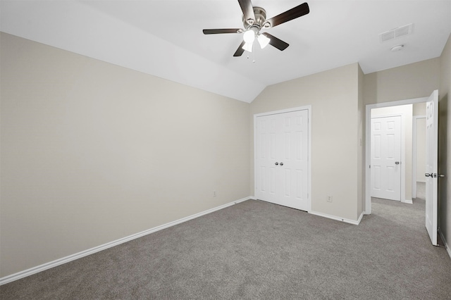 unfurnished bedroom featuring carpet floors, ceiling fan, vaulted ceiling, and a closet