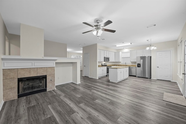 kitchen with white cabinets, appliances with stainless steel finishes, hardwood / wood-style flooring, and decorative light fixtures