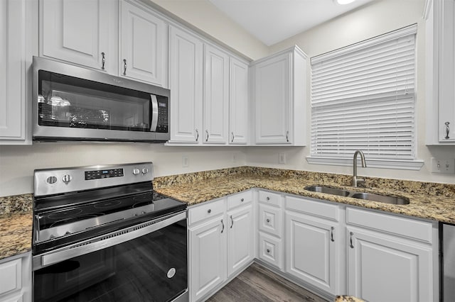 kitchen with white cabinetry, appliances with stainless steel finishes, dark stone counters, and sink