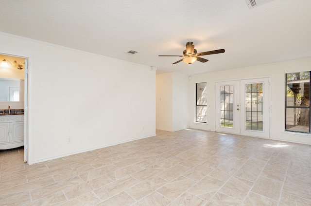 spare room with french doors, ceiling fan, sink, and a textured ceiling