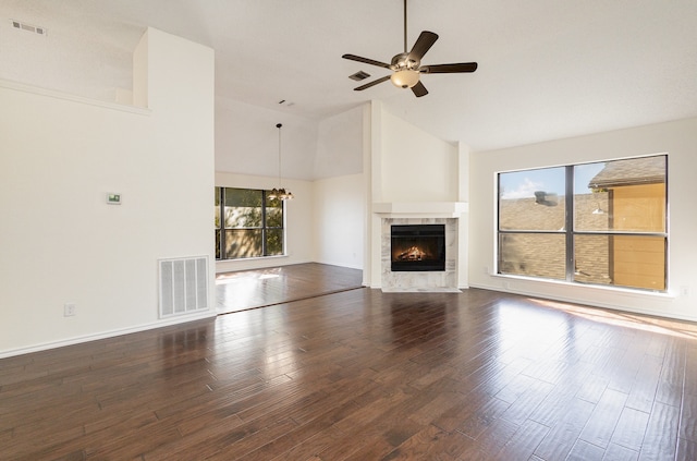 unfurnished living room with ceiling fan, dark hardwood / wood-style flooring, high vaulted ceiling, and a tiled fireplace