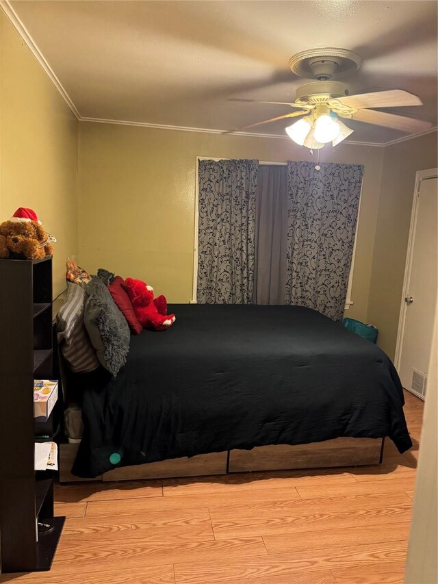 bedroom with crown molding, ceiling fan, and light hardwood / wood-style floors