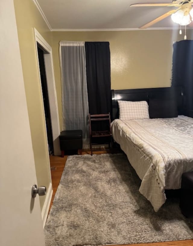 bedroom featuring dark hardwood / wood-style flooring, ceiling fan, and ornamental molding