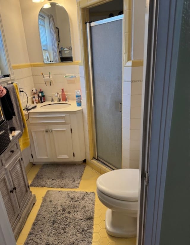 bathroom featuring tile walls, tile patterned flooring, vanity, an enclosed shower, and toilet