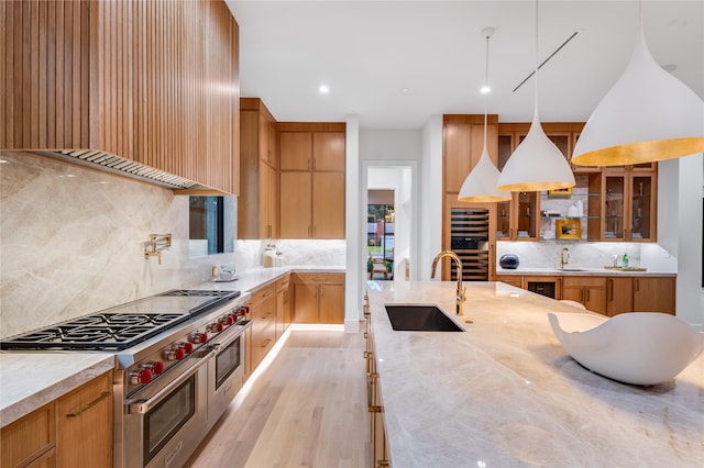 kitchen with sink, double oven range, hanging light fixtures, wall oven, and custom exhaust hood