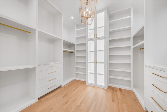 walk in closet with a chandelier and light wood-type flooring