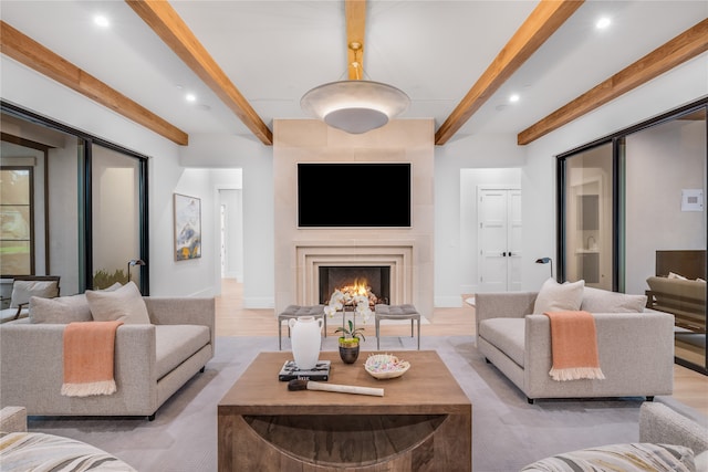 living room with a large fireplace, beamed ceiling, and light wood-type flooring