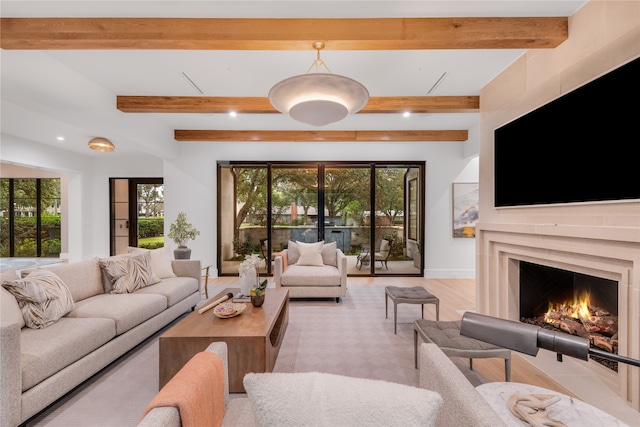 living room with beamed ceiling, plenty of natural light, and light hardwood / wood-style flooring