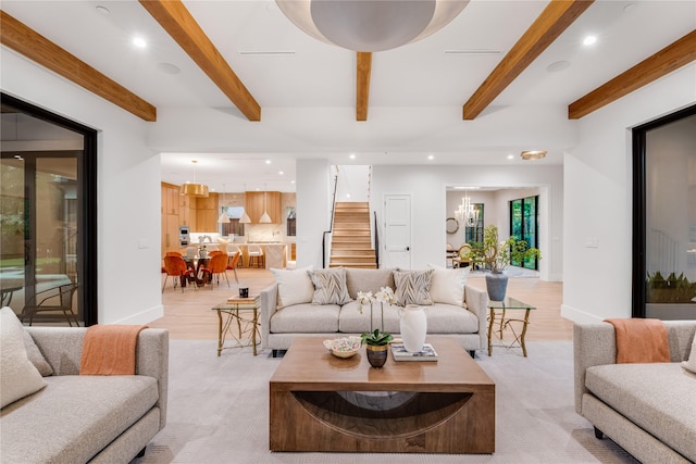 living room featuring a notable chandelier, beam ceiling, and light hardwood / wood-style floors