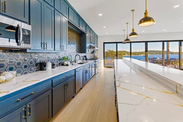 kitchen featuring sink, appliances with stainless steel finishes, pendant lighting, light stone countertops, and backsplash