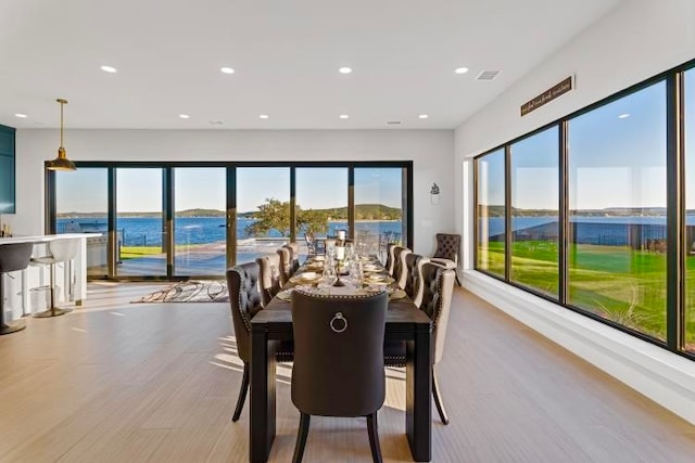 dining area with a water view and light wood-type flooring