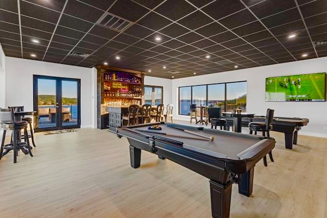 rec room with a drop ceiling, french doors, bar area, light wood-type flooring, and pool table