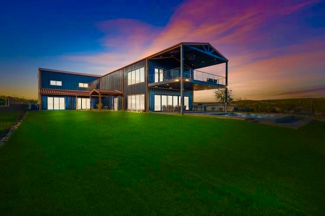 back house at dusk featuring a garage and a lawn