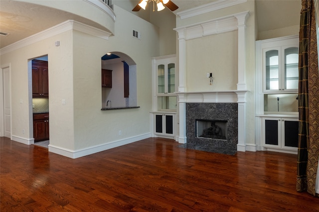 unfurnished living room with dark wood-type flooring, ceiling fan, a premium fireplace, and ornamental molding