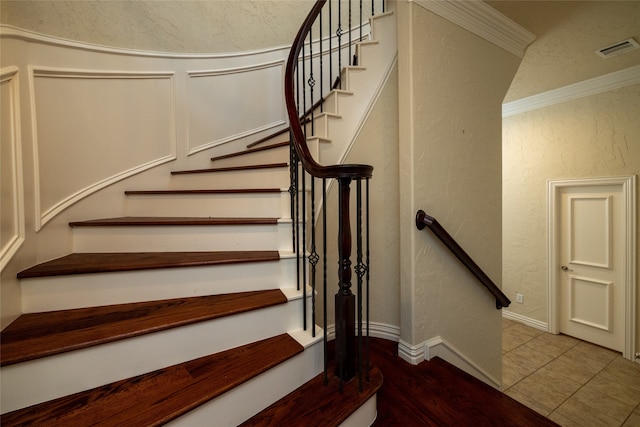 staircase with tile patterned floors and ornamental molding