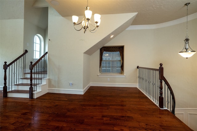 stairway with wood-type flooring, an inviting chandelier, and crown molding