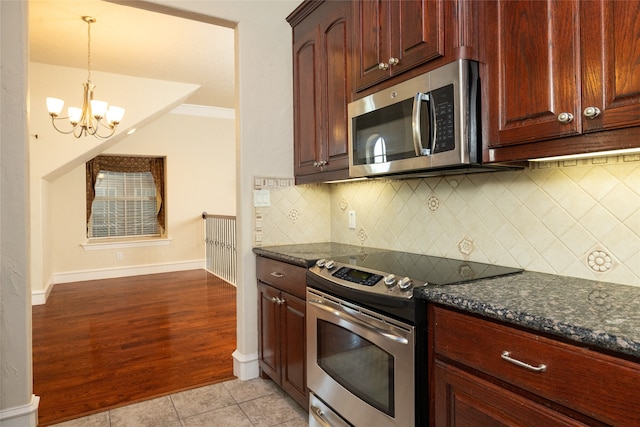 kitchen with stainless steel appliances, decorative backsplash, ornamental molding, light wood-type flooring, and dark stone countertops