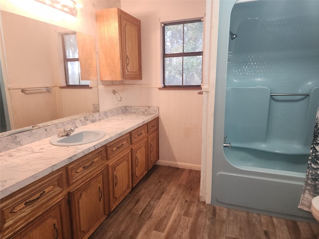 full bath with a wainscoted wall, wood finished floors, vanity, and shower / bathtub combination with curtain