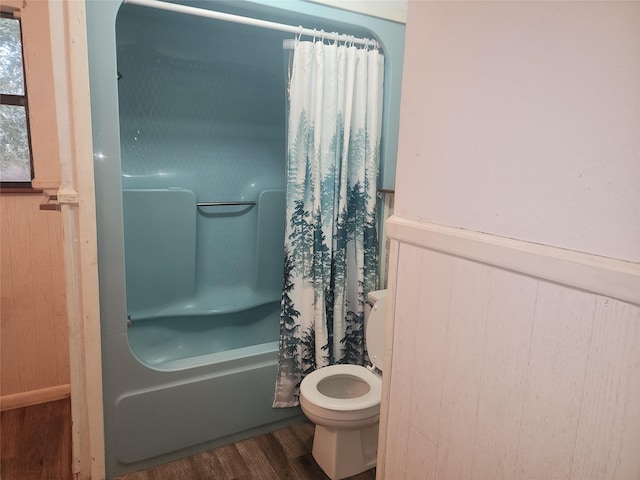 full bath with toilet, a wainscoted wall, wood walls, wood finished floors, and shower / bath combination with curtain