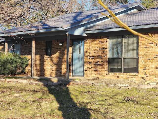 exterior space with a yard, metal roof, and brick siding