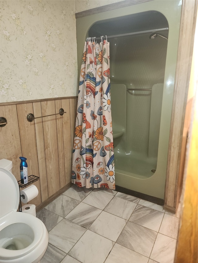 bathroom featuring curtained shower, wooden walls, and toilet