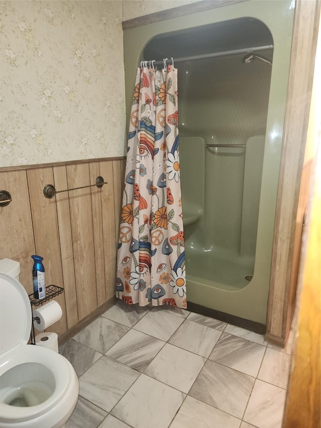 full bath featuring a stall shower, wainscoting, toilet, and wallpapered walls