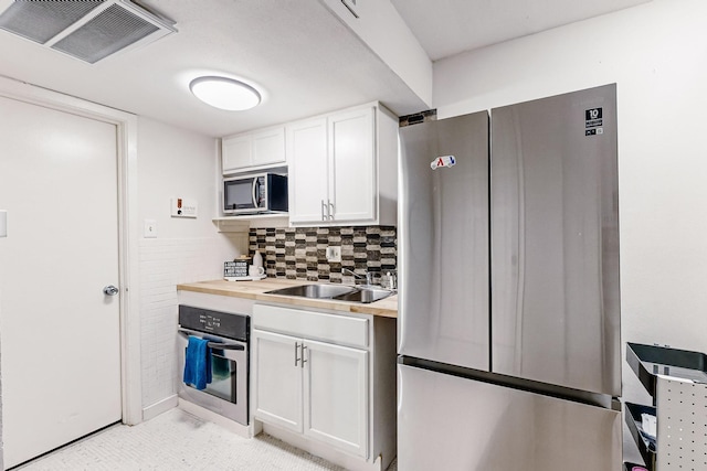 kitchen featuring sink, tasteful backsplash, wooden counters, appliances with stainless steel finishes, and white cabinets