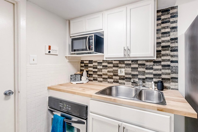 kitchen with butcher block countertops, white cabinets, and stainless steel appliances