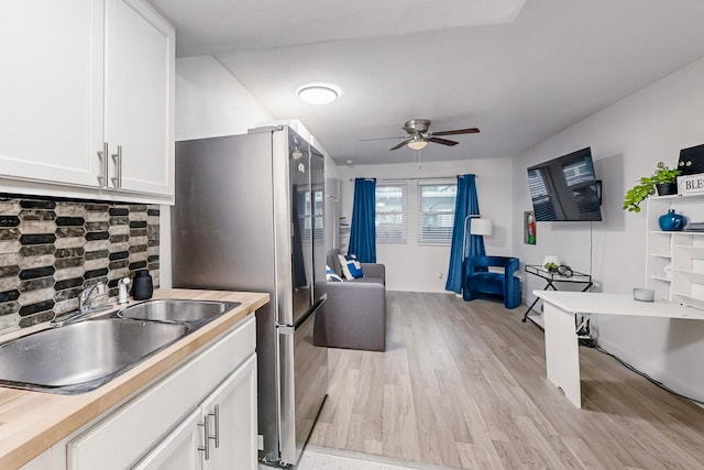 kitchen featuring light hardwood / wood-style floors, sink, decorative backsplash, and white cabinets