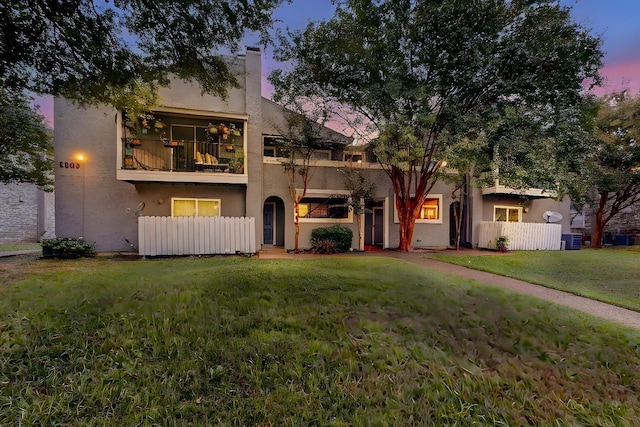 view of front of home with a balcony and a lawn